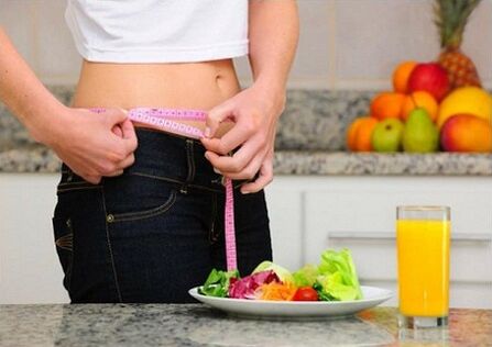 A girl losing weight during a diet measures her waist size